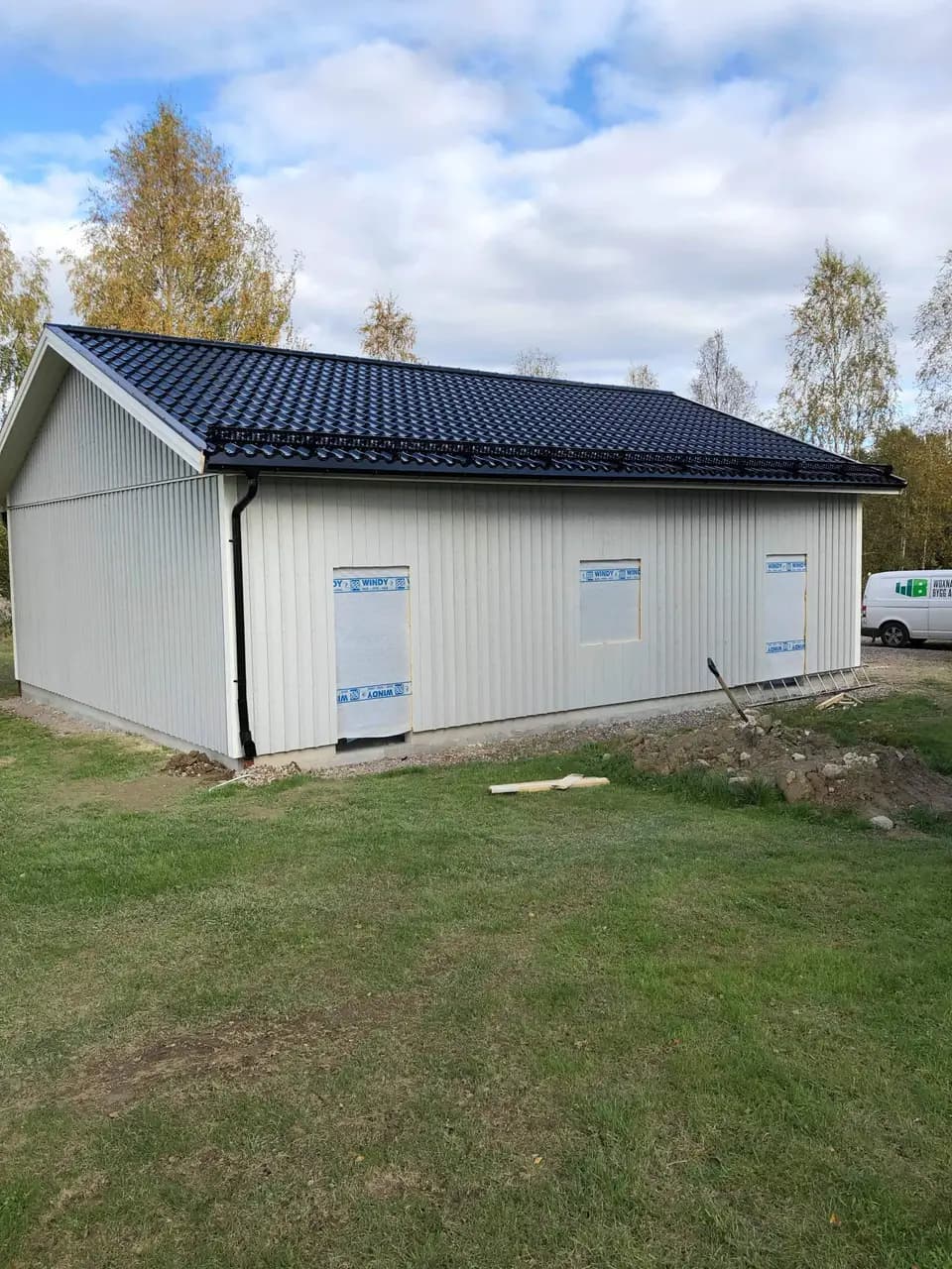 Nybyggd vit lagerbyggnad med svart plåttak