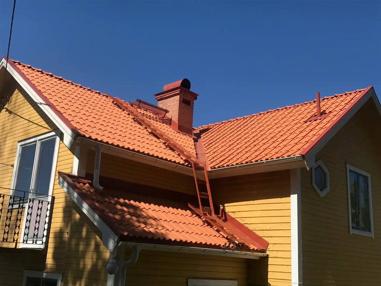 Nylagda tegelpannor på tak till gult hus