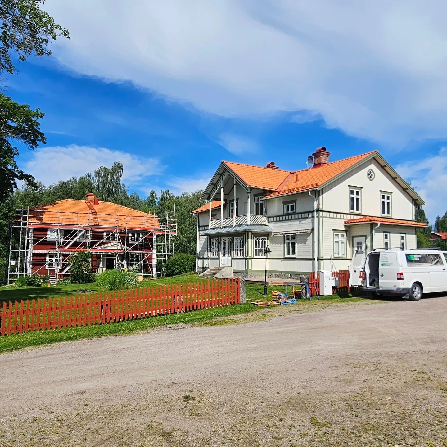 Två sekelskifteshus med nya tegeltak, det ena inklätt i byggställning